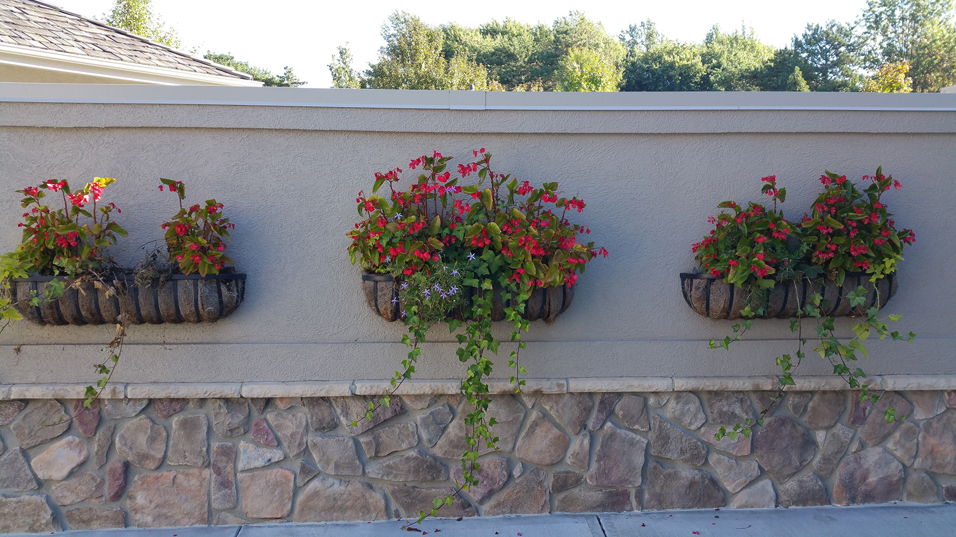 3 wall-hanging planters with red flowers installed by a home in Elkhorn, NE. 