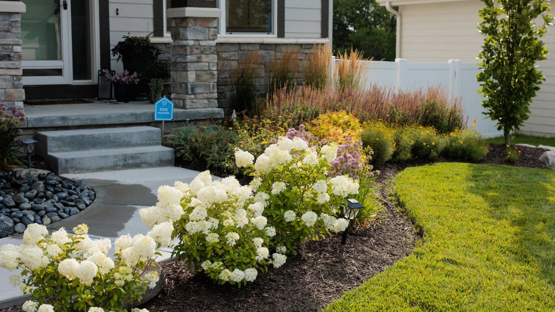 Inviting front garden with vibrant flowers and decorative plants framing the entrance of a home.