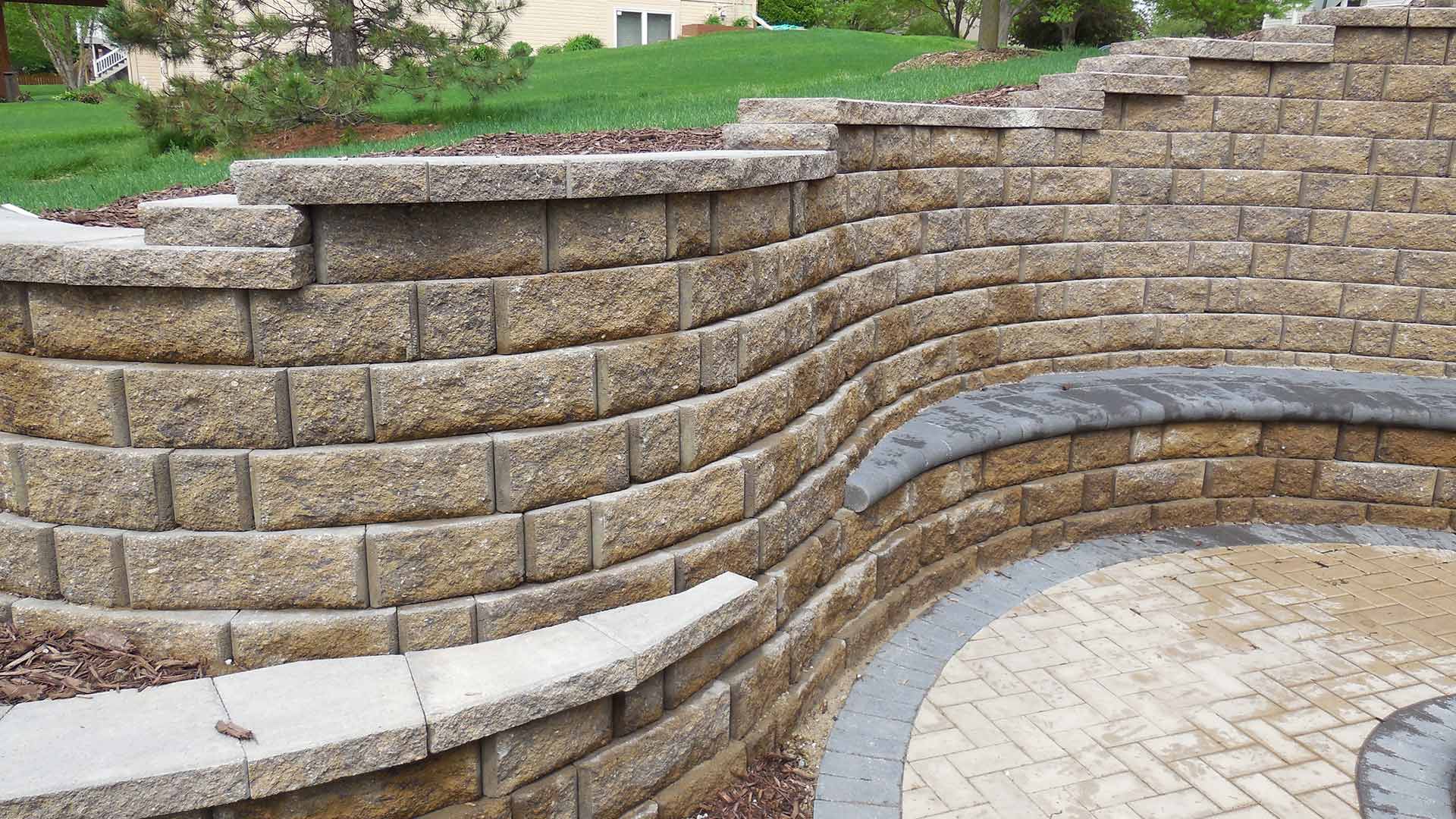 A custom curved stone retaining wall around a sloped property in Gretna, Nebraska.