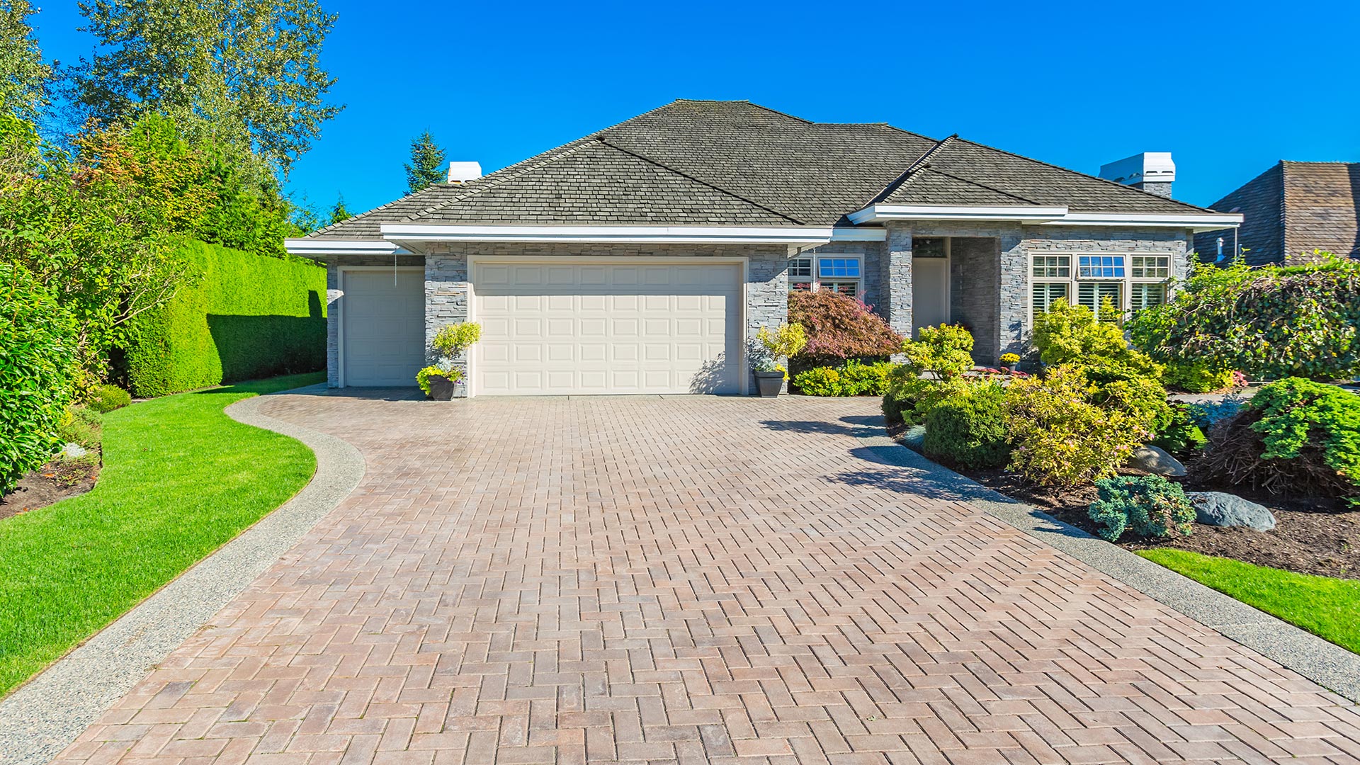 A custom paver driveway installed in front of a home with beautiful landscaping in Bennington, NE. 
