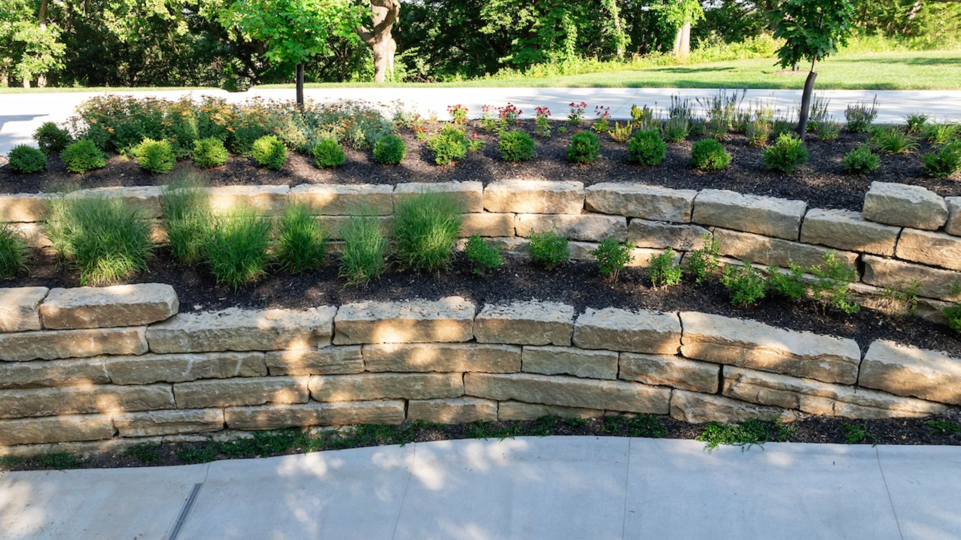 Beautiful terraced garden design featuring natural stone walls and a variety of lush plants and flowers.