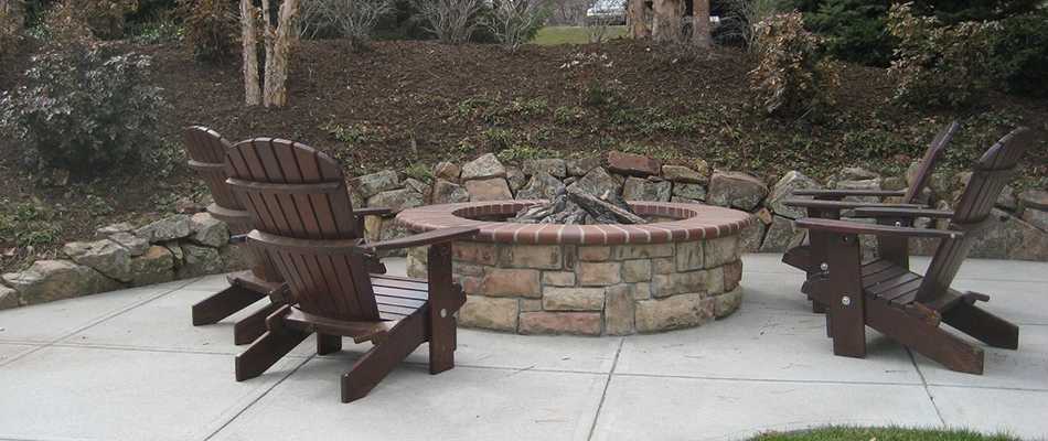 A profile angle of a brick fire pit surrounded by wooden chairs in Gretna, NE. 
