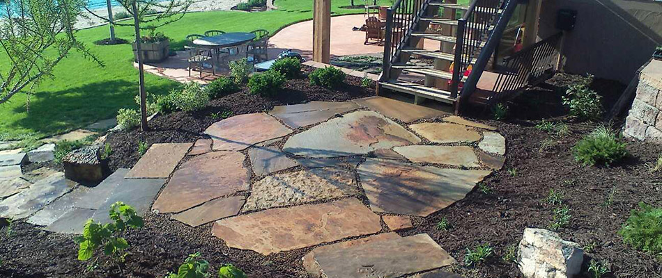 A multi-colored, multi-leveled flagstone patio with steps installed in an Omaha, NE backyard. 
