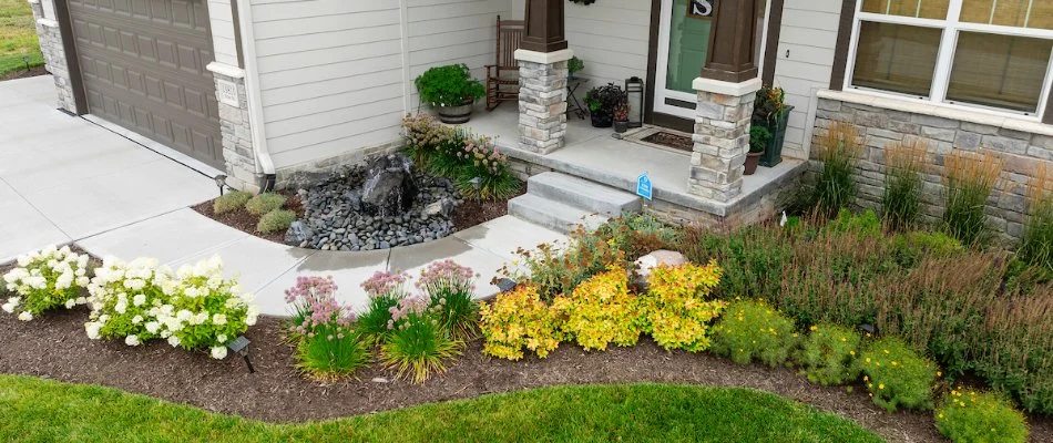 Landscape bed in the front yard of a property in Gretna, NE, with a water feature.