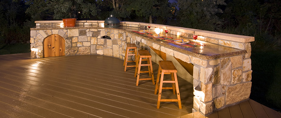 A custom outdoor kitchen complete with lighting and pizza oven behind a home in Bennington, NE.