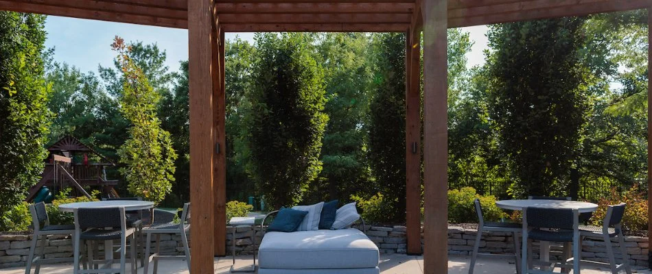 Pergola seating area with furniture and greenery.