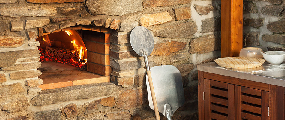 A stone pizza oven feature added to an outdoor kitchen behind a home in Ralston, NE. 