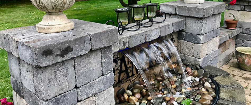 A pondless waterfall feature installed into a stone retaining wall behind a home in Ralston, NE. 